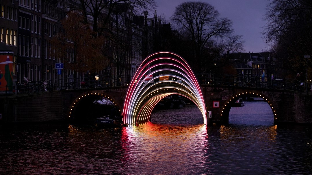 Lichtkunstwerk in de vorm van bogen boven een Amsterdamse gracht tijdens het Amsterdam Light Festival